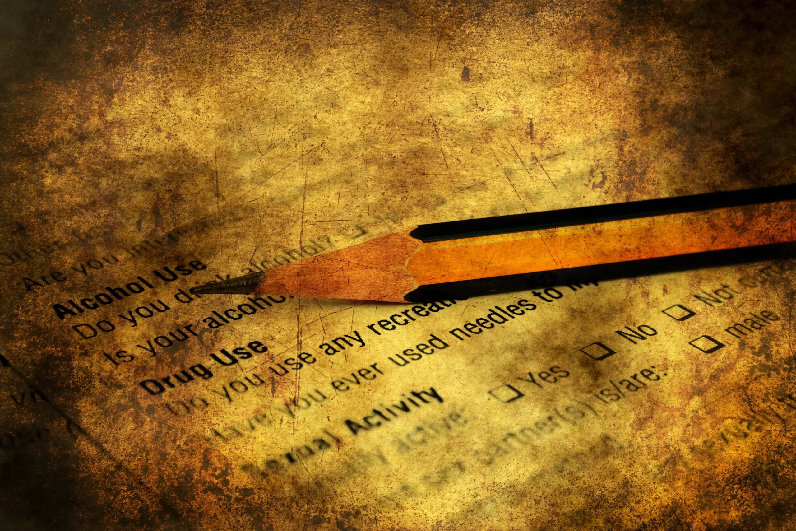 Alcohol and drug policy in the workplace. A pencil resting on a weathered piece of paper with type-written wording printed on it.