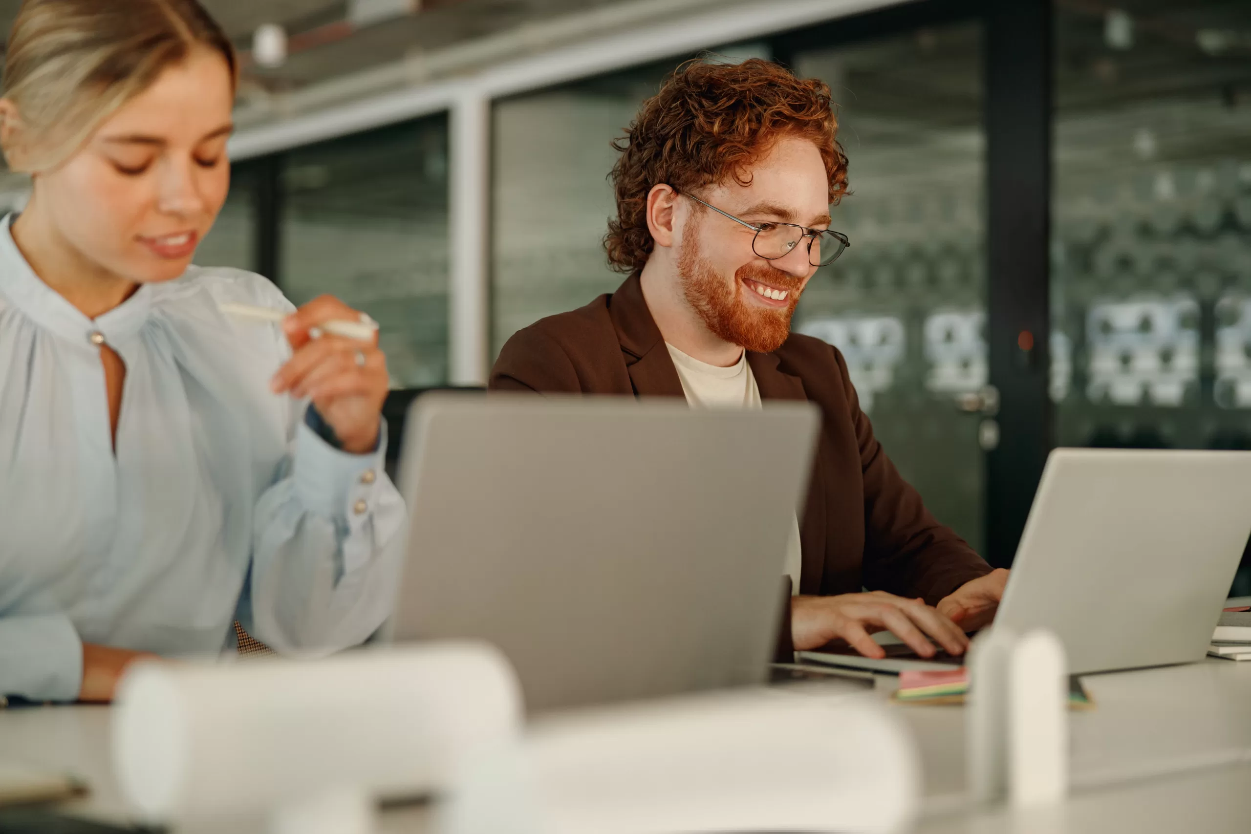 Productive work environment - Female and male office workers laughing sat at their respective laptops in an office environment